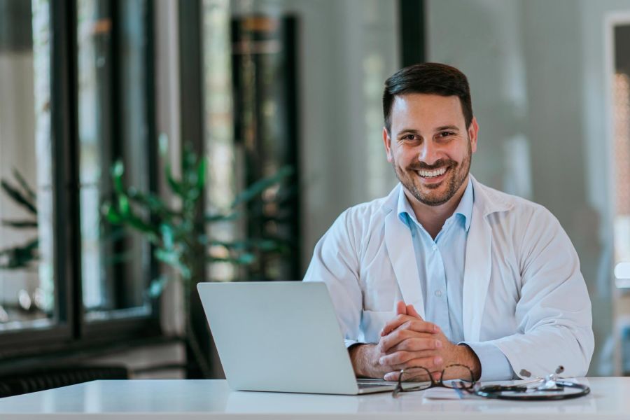 smiling doctor with laptop at desk