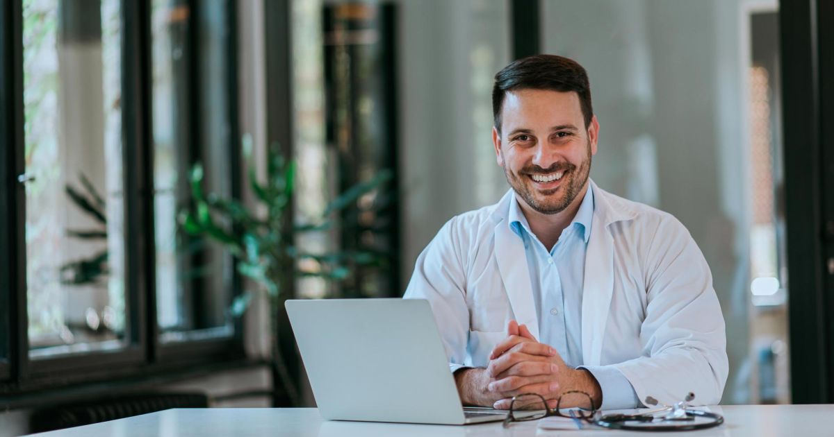 smiling doctor with laptop at desk